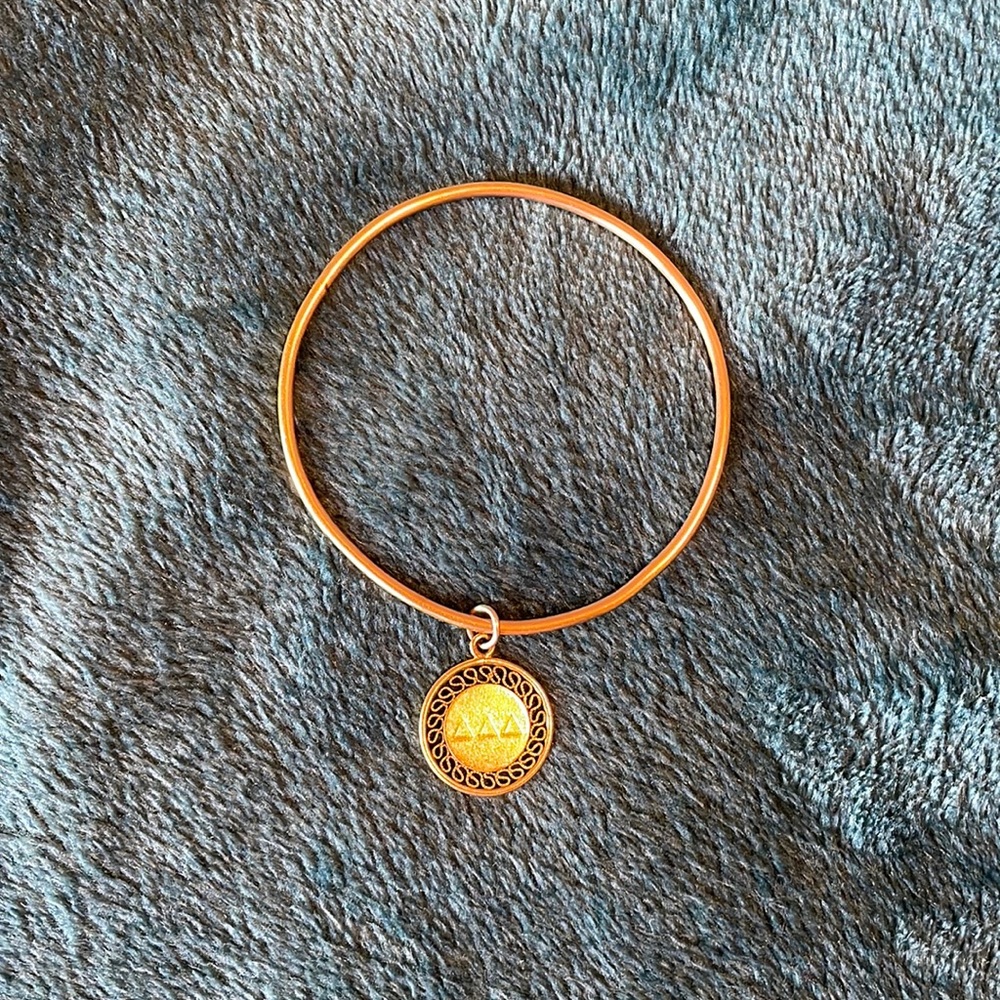 Gold sorority logo bracelet.